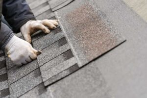 A close-up of a residential roof with faded shingles and visible storm debris on the surface.