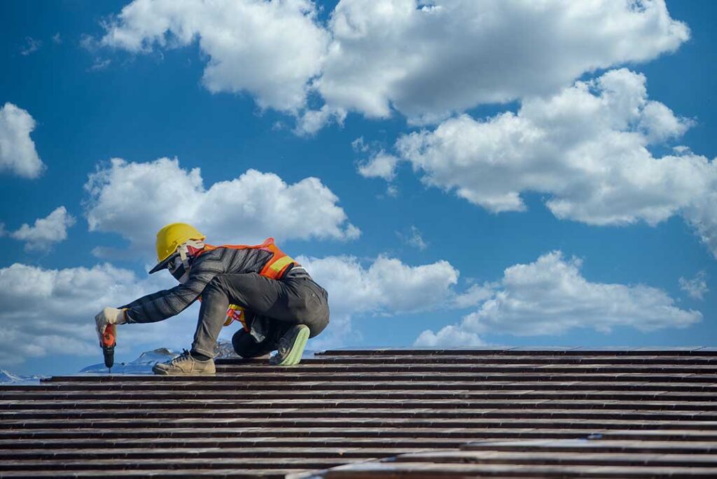 A homeowner examining roof shingles and flashing for signs of water damage.